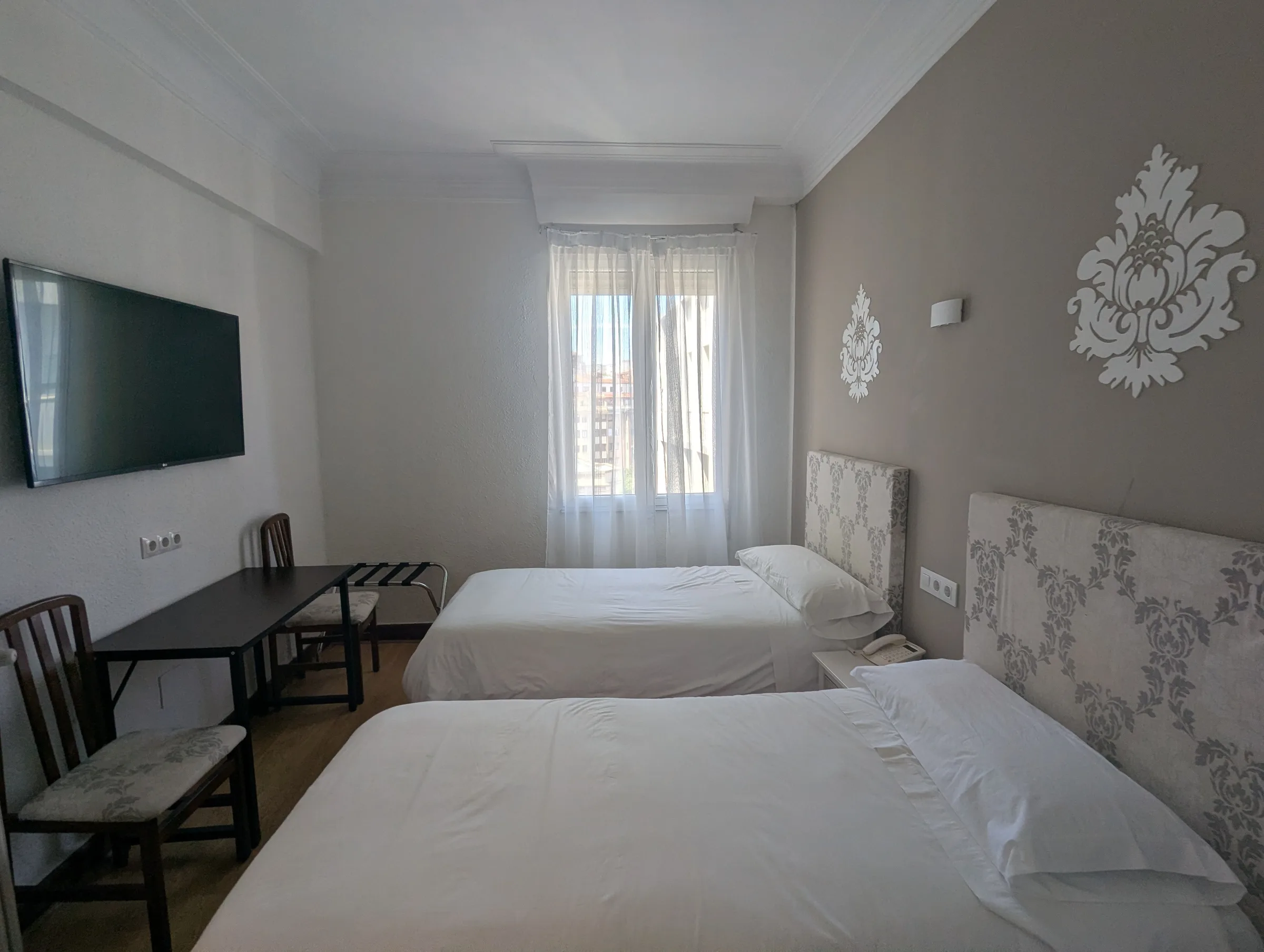 Zona de salón de habitación doble con vistas en Hostal La Mexicana Santander con sillón y luz natural