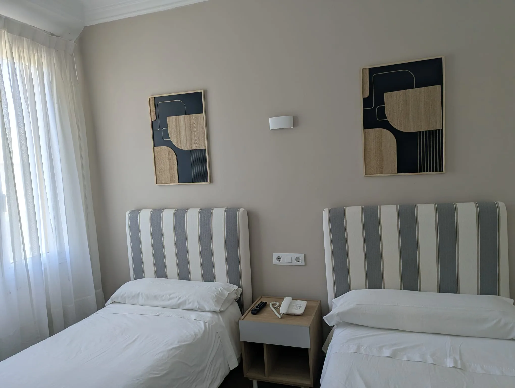 Cabeceros tapizados de rayas azul y blanco con cuadros abstractos en habitación doble económica, Hostal La Mexicana Santander